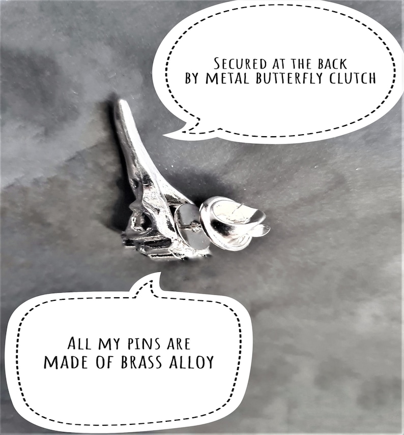 May include: A silver metal pin shaped like the Eiffel Tower with a butterfly clasp on the back. The pin is made of brass alloy. "SECURED AT THE BACK BY METAL BUTTERFLY CLUTCH" and "ALL MY PINS ARE MADE OF BRASS ALLOY" are written in black text on white speech bubbles.