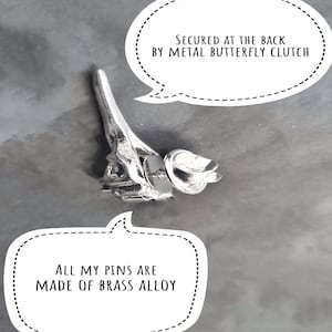 Puede incluir: Un pin de metal plateado con forma de la Torre Eiffel. El pin est&aacute; asegurado en la parte posterior con un cierre de mariposa de metal. "Todos mis pines est&aacute;n hechos de aleaci&oacute;n de lat&oacute;n" est&aacute; escrito en un globo de di&aacute;logo blanco.