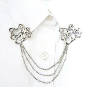 May include: Silver octopus brooch with a chain attached. The octopus is detailed with textured tentacles and a beaded body.