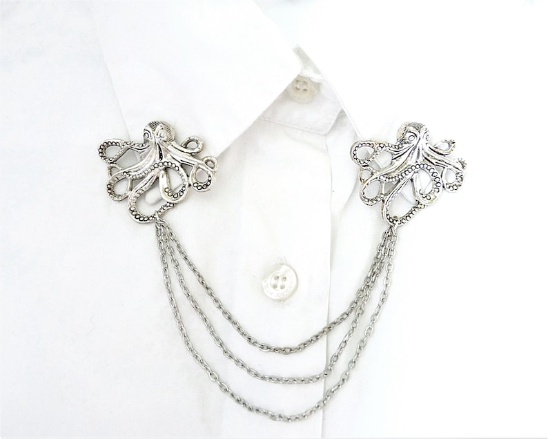 May include: Silver octopus brooch with a chain attached. The octopus is detailed with textured tentacles and a beaded body.