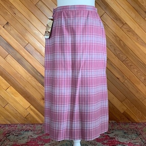 May include: A pink plaid skirt with a straight silhouette. The skirt features a pattern of vertical and horizontal lines in shades of pink and lavender. A tag is attached to the skirt. The skirt is displayed on a white mannequin.