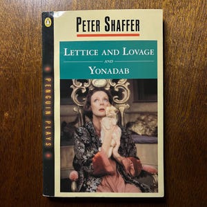Pode incluir: Um livro de bolso de Peter Shaffer, "Lettice and Lovage and Yonadab". A capa apresenta uma mulher segurando um gato, com um fundo verde-azulado e creme. O logotipo da Penguin Plays é visível na lombada.