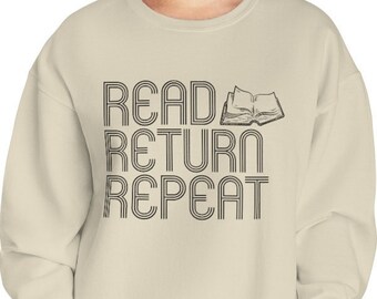 May include: A light beige sweatshirt with the text "READ RETURN REPEAT" in black, with a stylized image of an open book above the word "READ".
