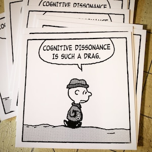 May include: Black and white illustration of a cartoon character with a speech bubble that says "Cognitive dissonance is such a drag."