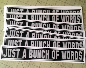 May include: A stack of white stickers with black borders and gray text that reads "JUST A BUNCH OF WORDS".