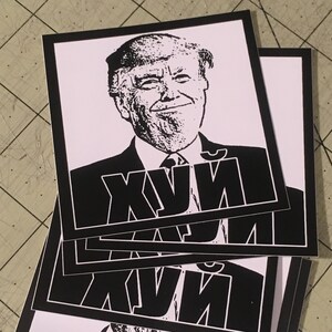 May include: Black and white sticker with a portrait of a man with a serious expression. The word "XYЙ" is printed in large, bold letters below the portrait.