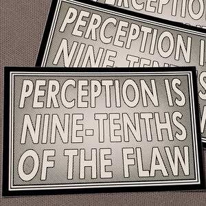 May include: Black and white sticker with the text "Perception is nine-tenths of the flaw."