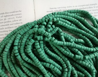 May include: A close-up of a pile of green, coiled, ceramic beads. The beads are small and have a rough texture.