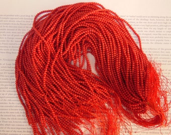 May include: A large pile of bright red coral beads, perfect for jewelry making or crafting projects.