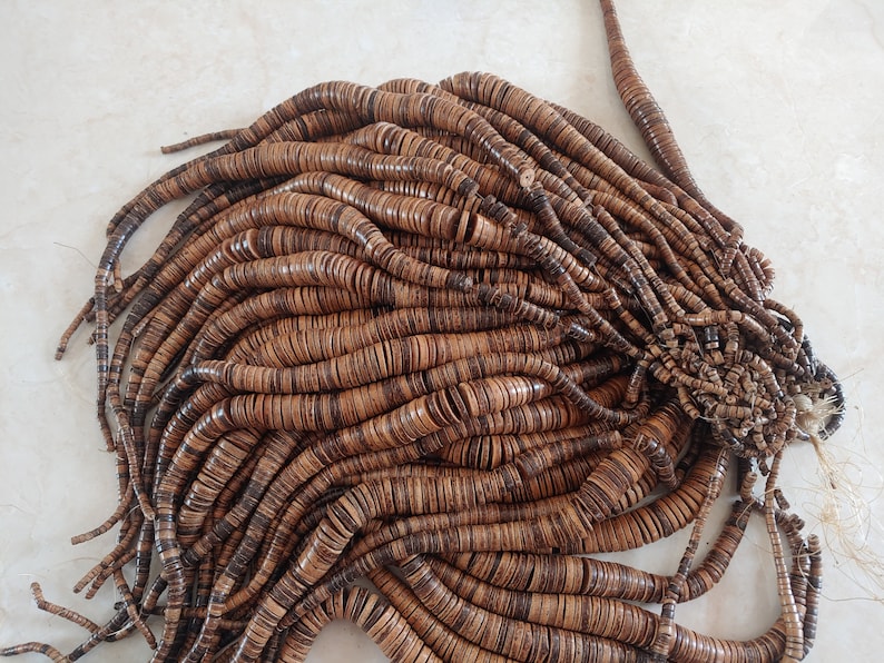 May include: A large pile of brown wooden beads, each bead is a flat disc with a dark brown centre and a lighter brown outer edge.