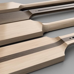 May include: Four unfinished guitar necks made of wood with a dark wood inlay. The necks are arranged in a row, with the top neck being the most complete.
