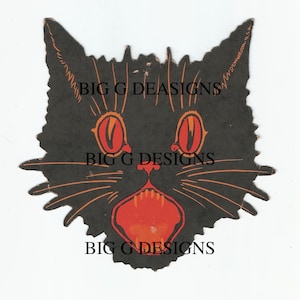 May include: Black paper cutout of a cat's face with large red eyes and an open mouth with red teeth. The cat's whiskers are orange. The text "Dennison U.S.A." is printed on the right side of the cutout.