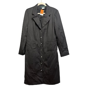 May include: A dark gray, long-line blazer with a button-down front and two front pockets. The blazer is hanging on a white hanger. The blazer has a tag attached to it.