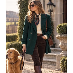 May include: A dark green double-breasted coat worn over a cream cable-knit sweater, dark brown corduroy trousers, and a brown leather belt. A plaid neck scarf, brown leather boots, and a brown leather shoulder bag complete the outfit.