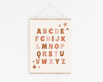 May include: A beige printable poster with the alphabet in brown, pink, and orange letters. The letters are in a retro font and are arranged in rows. There are small stars in the corners of the poster.
