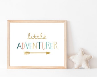 May include: A framed print with a white background and the text "little ADVENTURER" in colorful letters with a gold arrow pointing to the right.