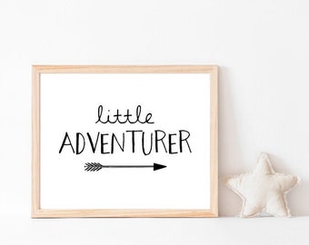 May include: A framed print with a white background and black text that reads "little adventurer" with a black arrow pointing to the right.