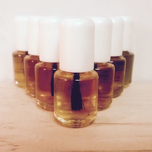 May include: A group of ten small, clear glass bottles with white caps and black applicators. The bottles are filled with a light amber liquid.