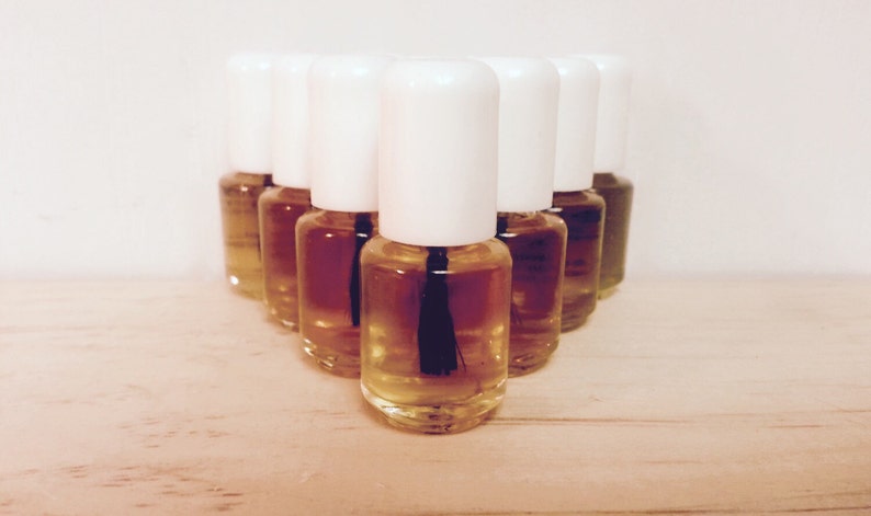 May include: A group of ten small, clear glass bottles with white caps and black applicators. The bottles are filled with a light amber liquid.