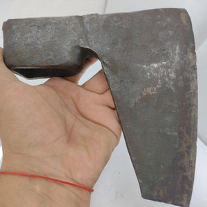 May include: A rusty, antique axe with a wooden handle. The axe head is shaped like a broad blade with a curved edge.