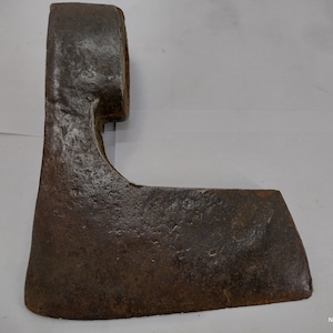 May include: A rusty, antique axe head with a curved blade and a rounded eye for the handle. The axe head is made of metal and has a dark brown patina.