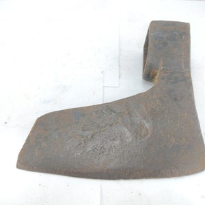 May include: A vintage, rusty axe head with a curved blade and a loop for a handle. The metal has a weathered appearance, showing signs of age and use. The axe head is a tool for chopping wood.