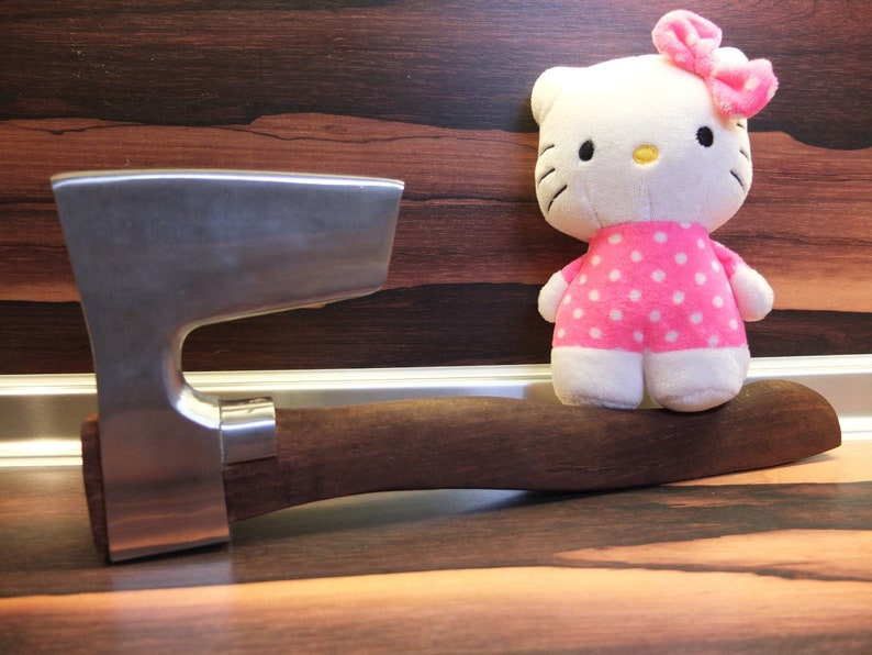 May include: A silver axe with a wooden handle and a pink and white polka dot plush toy sitting on the handle.