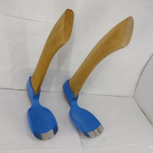 May include: Two wooden handled carving tools with blue painted metal blades. The tools are curved and have a spoon-like shape.