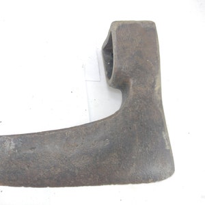May include: A vintage, single-headed axe with a curved blade and a rounded eye for the handle. The axe is made of metal and has a dark gray patina.