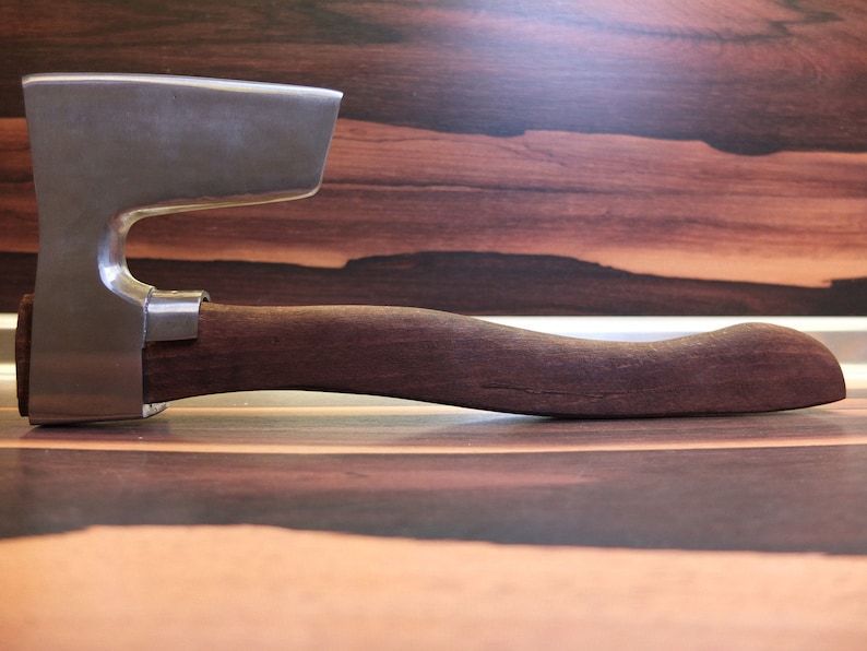 May include: A silver axe with a wooden handle. The axe has a curved blade and a rounded handle.