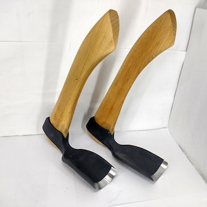 May include: Two wooden handled carving tools with black and silver metal blades. The tools are on a white surface.