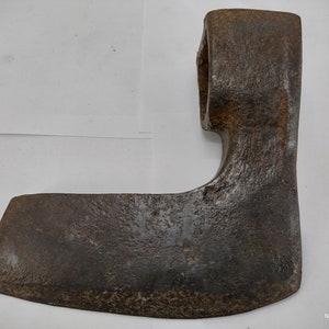 May include: A rusty, antique hand axe with a curved blade and a wooden handle. The axe is made of metal and has a worn, aged appearance.
