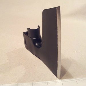 May include: Black metal axe head with a sharp edge and a handle attachment. The axe head is about 6 inches long.