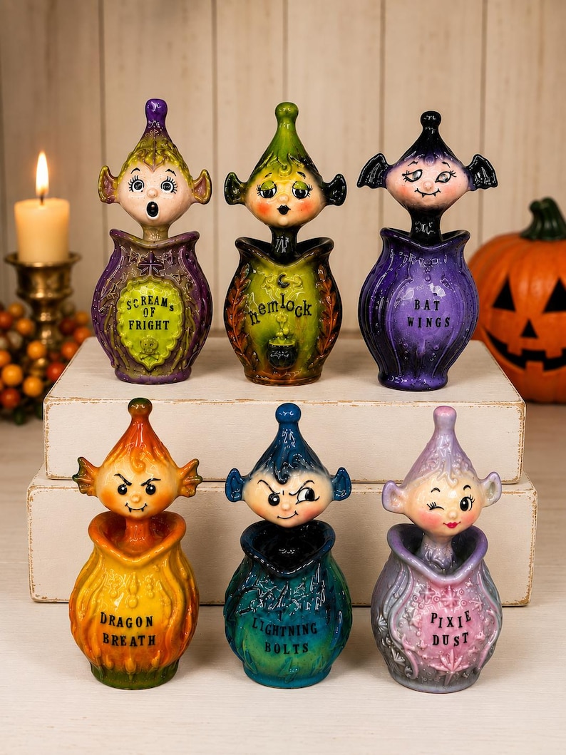 May include: A set of six decorative potion bottles with sculpted character stoppers. Each bottle features a unique color and label: Scream of Fright, Hemlock, Bat Wings, Dragon Breath, Lightning Bolts, and Pixie Dust. The figures have distinct facial expressions and head shapes.