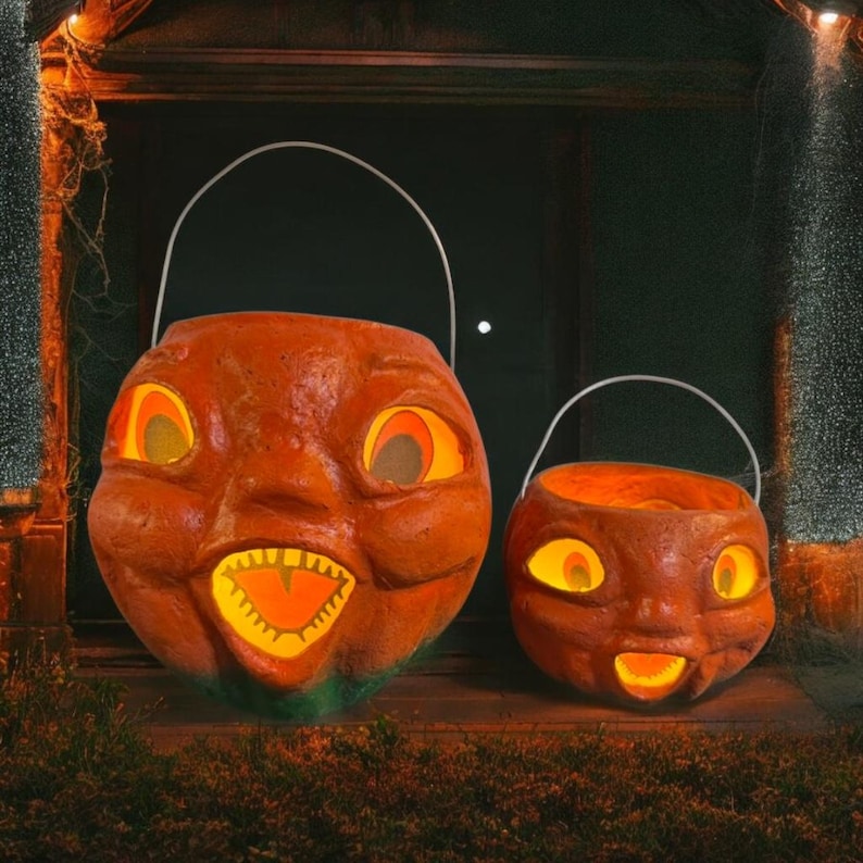 May include: Two orange Halloween pumpkin buckets with white handles. The pumpkins have carved faces with glowing yellow eyes and mouths. The larger pumpkin is on the left, and the smaller one is on the right.