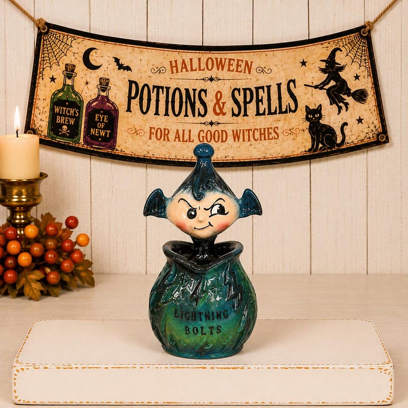 May include: A ceramic jar with a lid shaped like a mischievous imp with bat-like ears. The jar is teal and green with a glossy finish, featuring the text "LIGHTNING BOLTS" on the front. The lid is a dark blue, pointed figure with a smirk.
