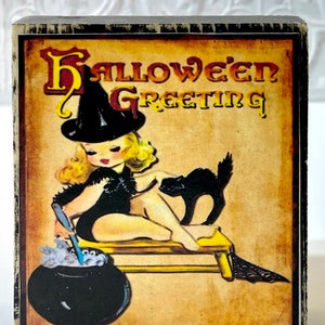 May include: A vintage Halloween greeting card featuring a witch with a black hat and a black cat. The witch is stirring a cauldron with a wooden spoon. The card has a yellowed background with the text "Halloween Greeting" in red and black lettering.