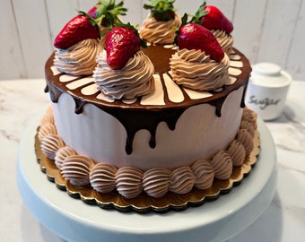 Può includere: Una torta rotonda con glassa marrone chiaro, guarnita con cinque fragole intere e ciuffi di crema al cioccolato. La parte superiore presenta un motivo a goccia di ganache al cioccolato fondente e la base è decorata con un bordo di crema al cioccolato.