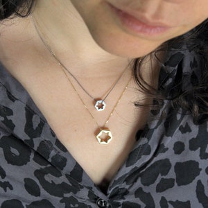 May include: Two silver necklaces with star-shaped pendants. The top necklace has a smaller star pendant, while the bottom necklace has a larger star pendant.