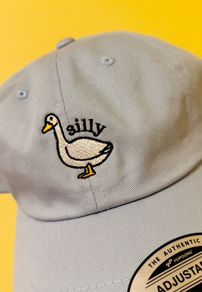 May include: A light blue baseball cap with an embroidered white duck and the word "silly" in black. The cap has an adjustable strap with a black label that says "The Authentic YUPOONG ADJUSTABLE".