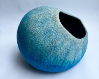 Könnte beinhalten: Ein blaues und weißes Filzkatzenbett in Form einer Halbkugel mit einer großen Öffnung.