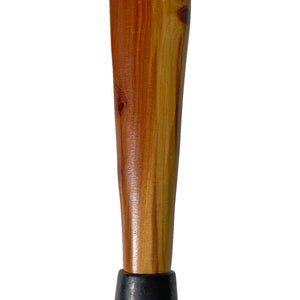 May include: A tapered wooden furniture leg with a natural wood grain finish. The leg is a warm brown color with lighter wood accents and a black rubber foot. The leg is designed to be attached to a piece of furniture.