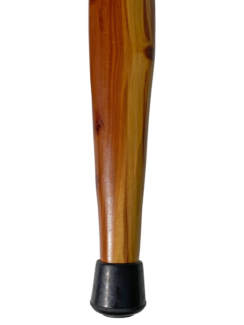 May include: A tapered wooden furniture leg with a natural wood grain finish. The leg is a warm brown color with lighter wood accents and a black rubber foot. The leg is designed to be attached to a piece of furniture.