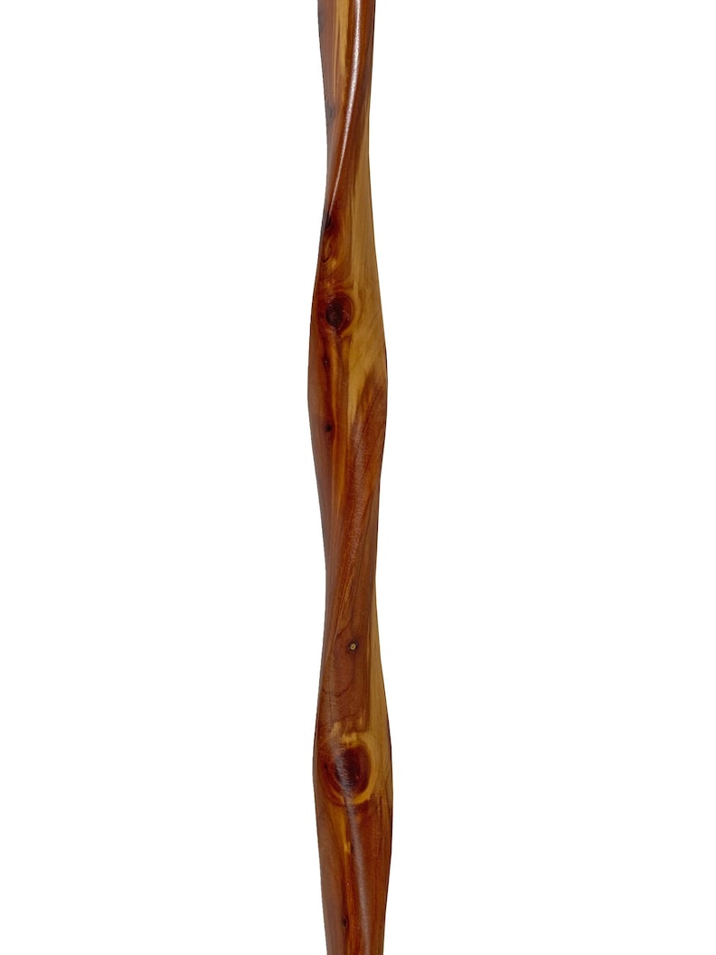 May include: A tall, wooden, decorative item with a twisted design. The wood is a warm brown color with visible knots and grain patterns. The item has a smooth, polished finish and is set against a white background.