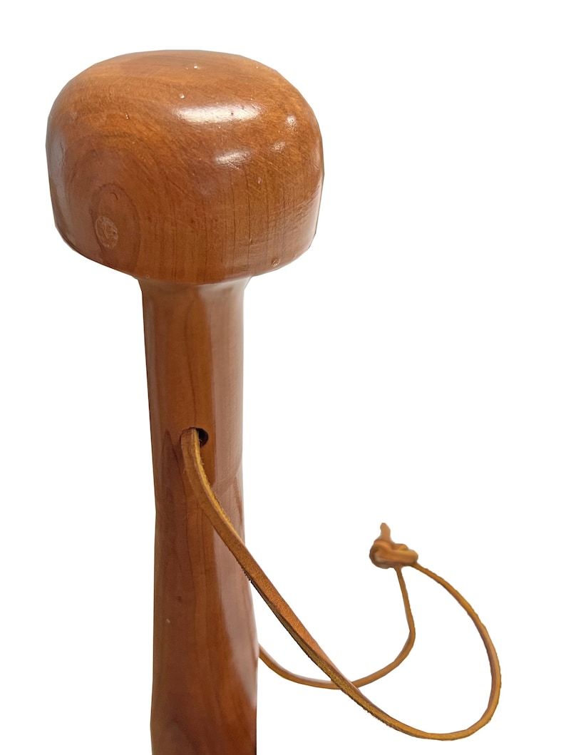 May include: A wooden walking cane with a rounded top and a smooth, polished finish. The cane is a warm brown color and features a leather wrist strap. The design is simple and classic, suitable for everyday use.