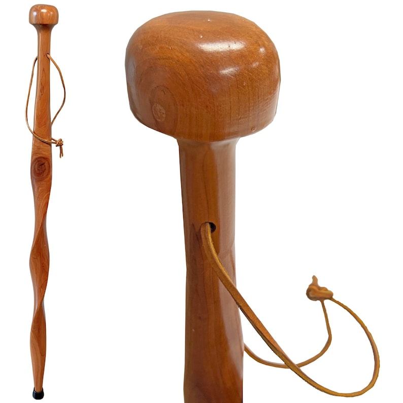 May include: A wooden walking cane with a light brown finish. The cane features a rounded top, a twisted shaft, and a leather wrist strap. The cane is approximately 36 inches in length.