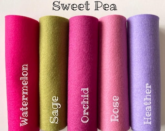 May include: Five rolls of felt fabric in different colors. The colors are watermelon pink, sage green, orchid pink, rose pink, and heather purple. The text "Sweet Pea" is at the top of the image. The text "Watermelon", "Sage", "Orchid", "Rose", and "Heather" are written vertically on the rolls of felt.