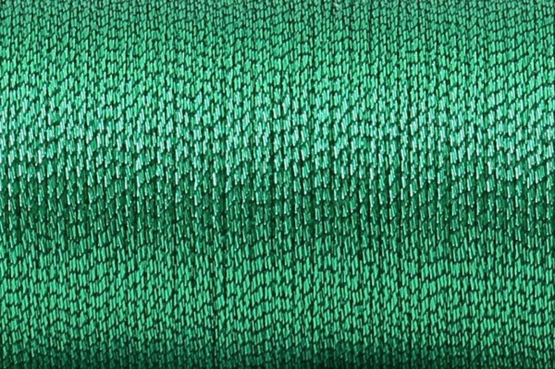 May include: Close-up of a spool of emerald green thread. The thread is tightly wound and has a slight sheen.