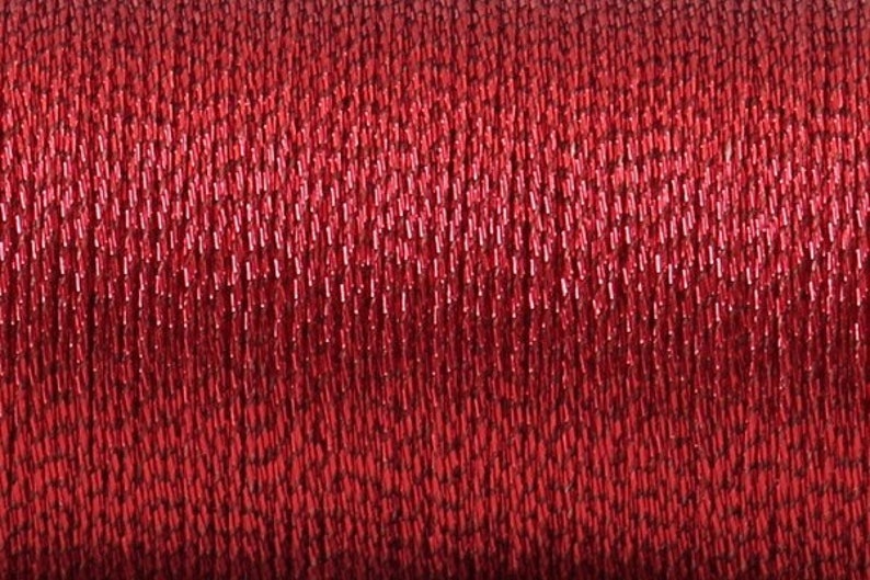 May include: Close-up of a spool of red metallic thread. The thread is shiny and has a slight shimmer.