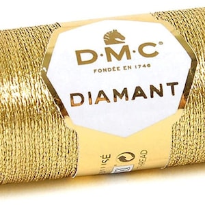 May include: A spool of gold metallic thread with the DMC Diamant brand label. The label features the DMC logo, the words "DMC" and "Diamant", and the text "Fondée en 1746".